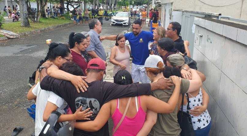 Funcionários rezavam em frente ao abrigo após o incêndio nesta sexta-feira (14)