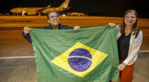 Roberto Carvalho e sua companheira Cristina Balbi se ajoelham para agradecer a chegada no Brasil no primeiro avião da FAB trazendo 211 brasileiros de Israel