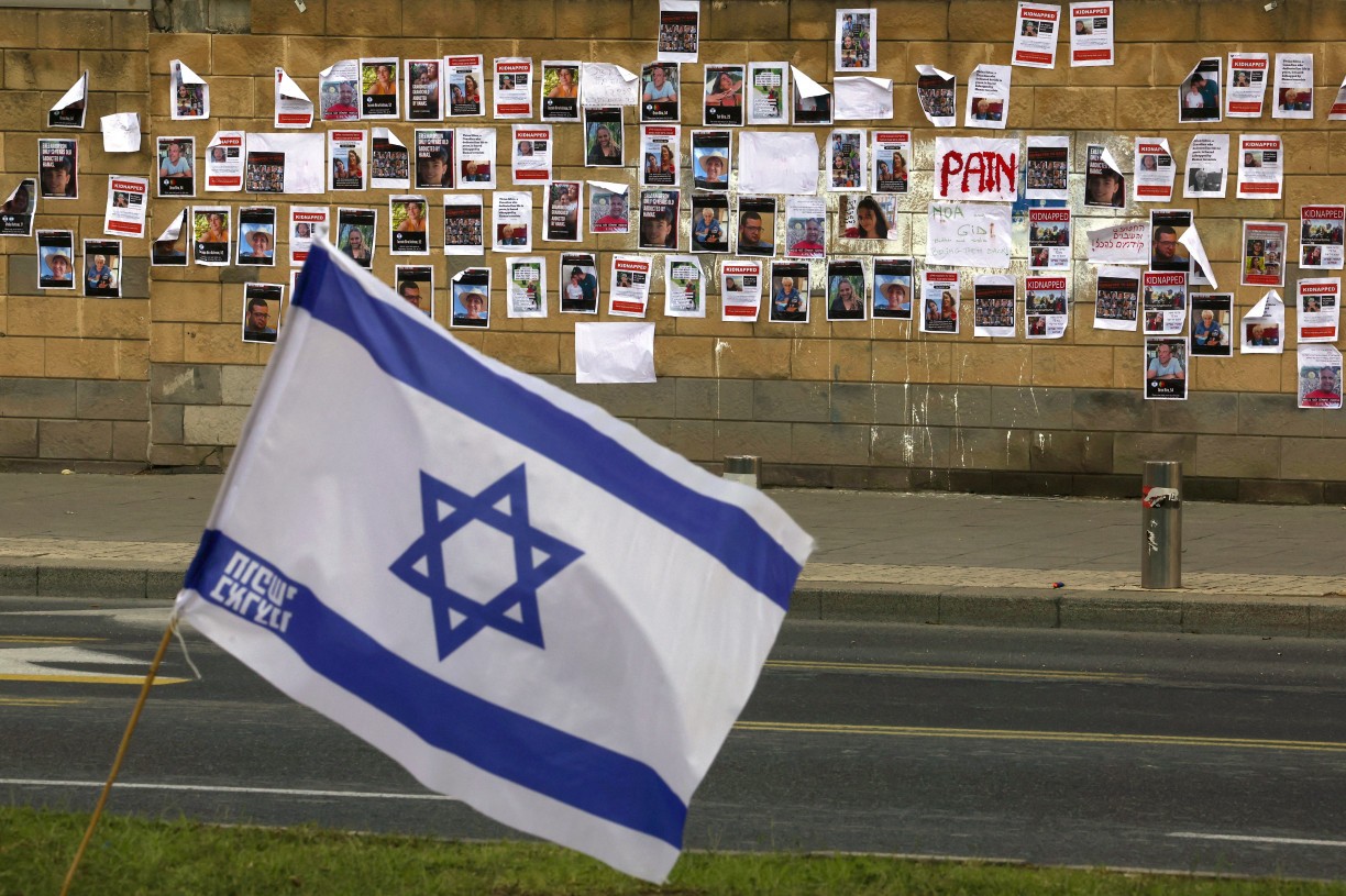 Bandeira israelense em frente a uma parede repleta de imagens de reféns israelenses sequestrados pelo grupo militante palestino Hamas 
