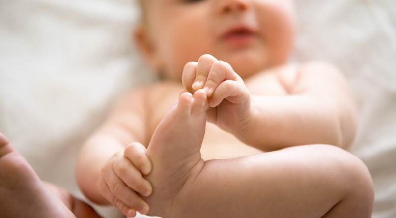 Imagem de bebê segurando o pé.