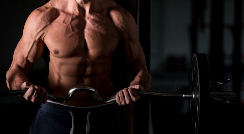Homem levantando uma barra na academia para aumentar massa muscular