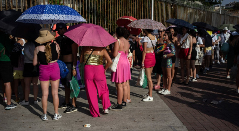F&atilde;s da Taylor Swift em fila para o Show da The Eras Tour no Rio de Janeiro. Pessoas usam guarda-chuvas para se proteger do sol