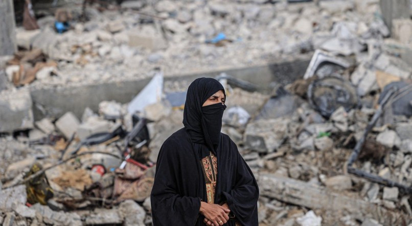 Mulher palestina em meio à destruição causada por ataques israelenses no vilarejo de Khuzaa, perto da cerca da fronteira entre Israel e o sul da Faixa de Gaza
