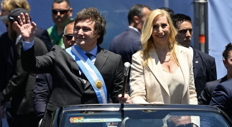 O novo presidente da Argentina, Javier Milei, acena para a multidão ao lado de sua irmã, Karina Milei, enquanto deixam o Congresso em um carro aberto durante sua cerimônia de posse em Buenos Aires, neste domingo (10)