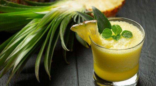 Suco de abacaxi ao lado da fruta