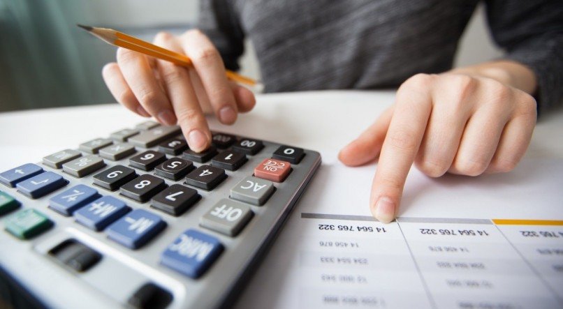 Closeup of accountant counting on calculator and working with table