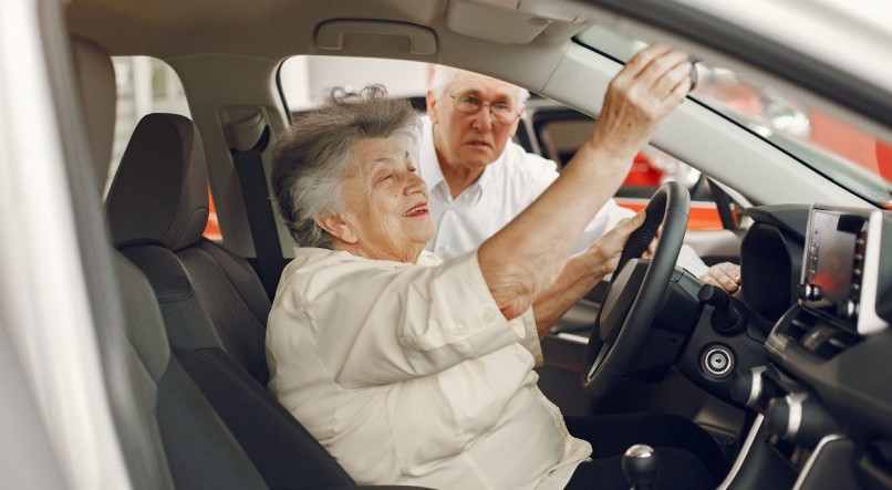 Old couple in a car salon. Family buying the car. Elegant woman with her husband. Senior by a car.