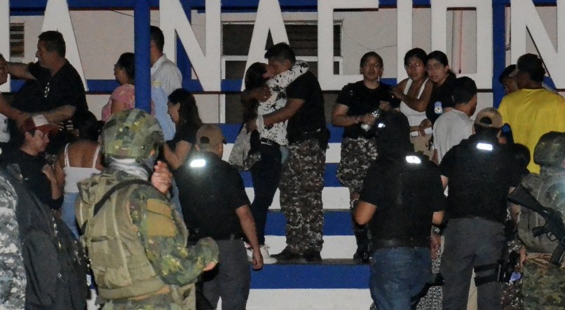 Um funcionário penitenciário (ao centro) que estava sendo mantido como refém por presidiários é abraçado por um parente após ser libertado da prisão de Machala, em Machala, Equador, no sábado (13) 