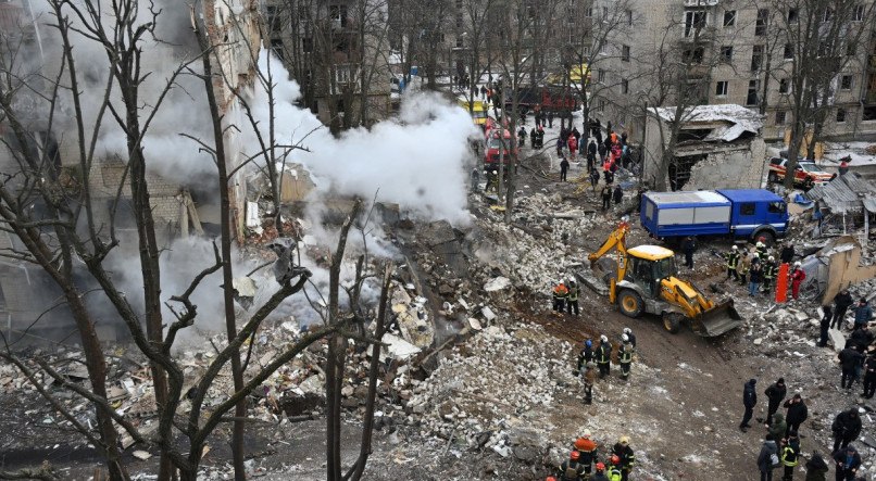 Equipes de resgate ucranianas limpam destroços no local de um ataque com mísseis em Kharkiv em 23 de janeiro de 2024, em meio à invasão russa da Ucrânia