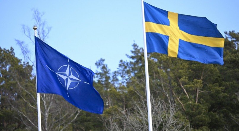 A bandeira da OTAN é erguida ao lado da bandeira da Suécia (R) em uma cerimônia na base naval de Musko, em Estocolmo, para marcar a entrada da Suécia na aliança