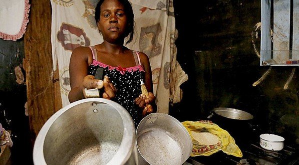Mulher em situação de vulnerabilidade segura panelas vazias na cozinha. Mães de Pernambuco terão benefício extra para custear alimentos e outros itens básicos
