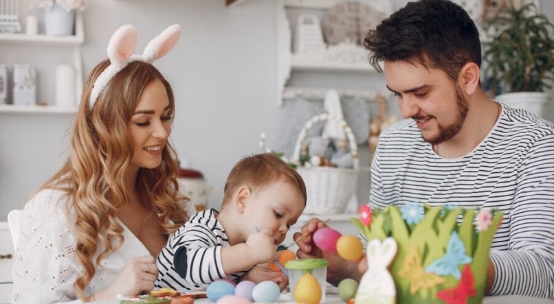 Família pintando ovos de Páscoa com criança