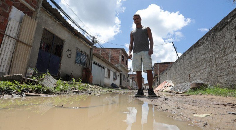 Morador Douglas Moura, de 27 anos, sofre para transportar o av&ocirc; cadeirante pela rua onde mora, em Nova Morada