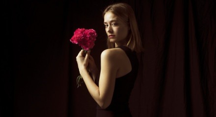 Mulher sedutora e confiante posa para foto com flores na mão