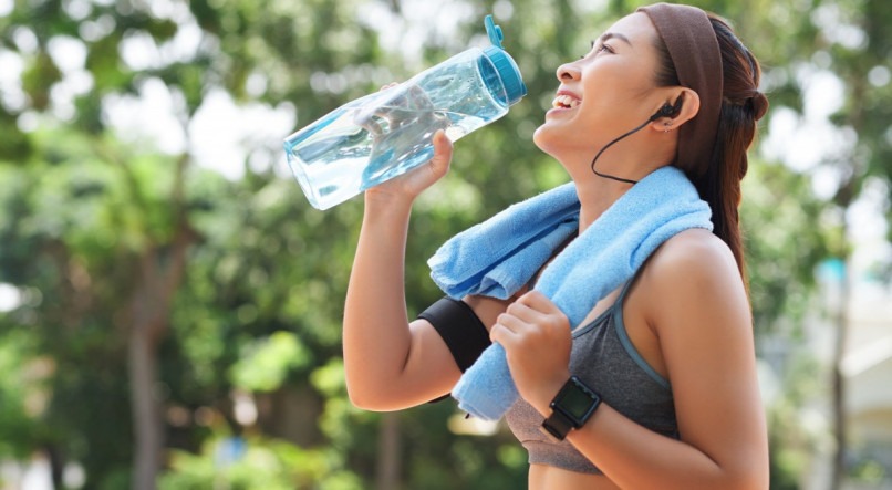 Imagem: Mulher bebendo água depois de praticar exercícios físicos no parque