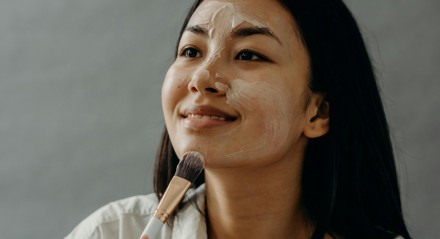 Mulher passando máscara de mamão e mel no rosto.