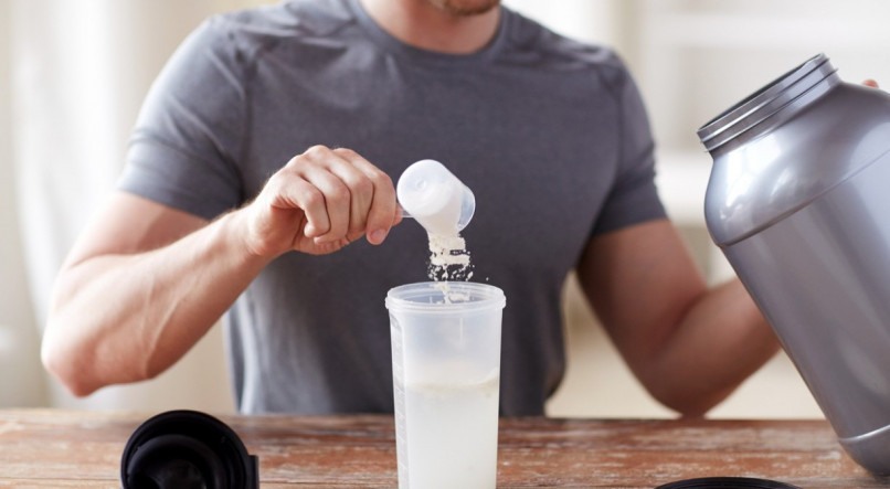 sport, fitness, healthy lifestyle and people concept - close up of man with jar and bottle preparing protein shake
