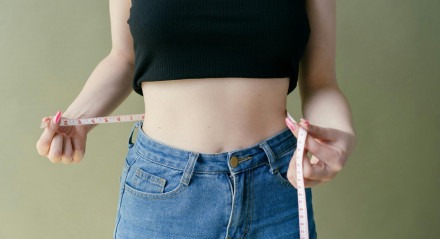 Mulher medindo a circunferência da cintura. 