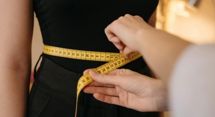 Mulher medindo a sua cintura. 