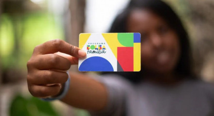 Imagem ilustrando mulher segurando o cartão do Bolsa Família 