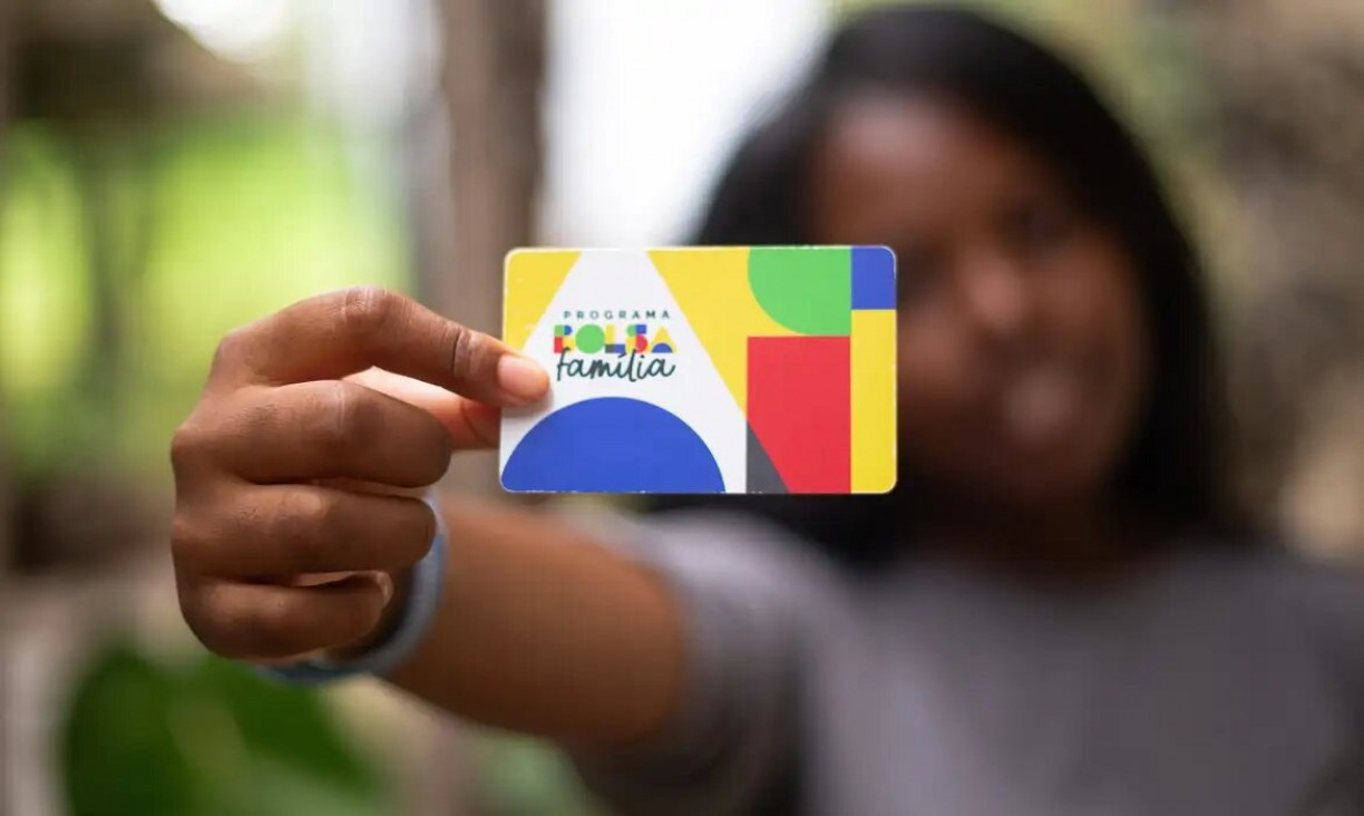 Imagem ilustrando mulher segurando o cartão do Bolsa Família 