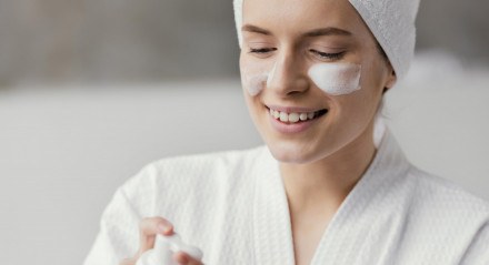 Mulher passando creme no rosto após sair do banho.