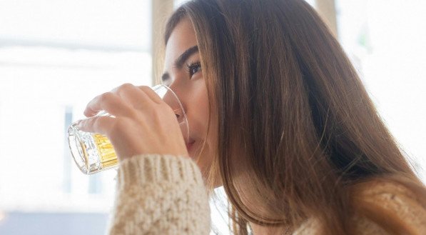 Mulher de cabelo longo bebendo cerveja.