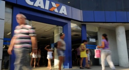 Imagem ilustrativa da agência da CAIXA com pessoas circulando em frente; os bancos sofrem alteração no funcionamento da terça-feira, 23 de abril