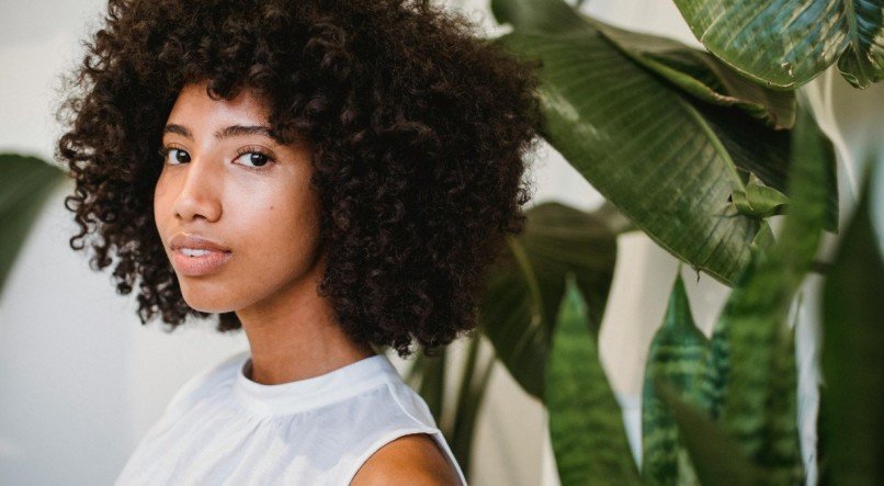 Mulher com cabelo cacheado olhando para frente.