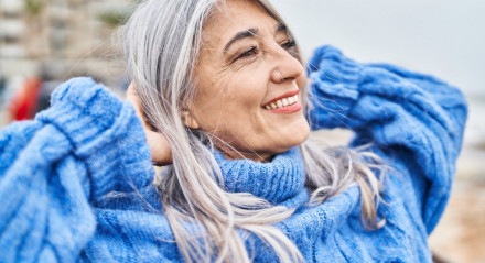Imagem de mulher de meia-idade com cabelos grisalhos com expressão relaxada
