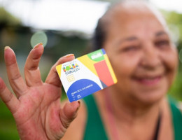 Imagem de beneficiária do Bolsa Família segurando o cartão do programa