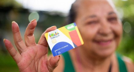 Imagem de beneficiária do Bolsa Família segurando o cartão do programa