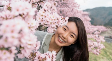 Imagem: Mulher jovem no meio de árvores, sorrindo para câmera