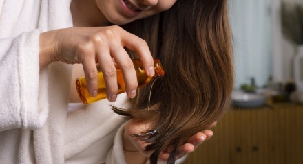 Mulher aplicando óleo no cabelo 