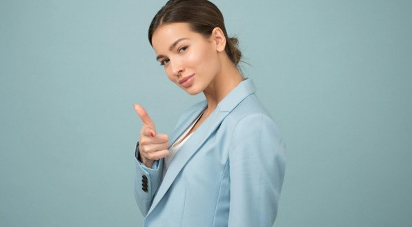 Imagem de mulher vestida com blazer azul apontando para frente