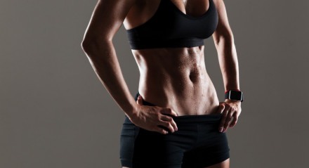 Cropped photo of amazing young sports woman body standing isolated over grey wall.