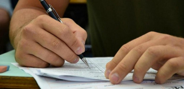 Imagem ilustrativa de uma mão segurando uma caneta sobre uma prova; testes do Concurso Público Nacional Unificado (CPNU) acontecem em maio