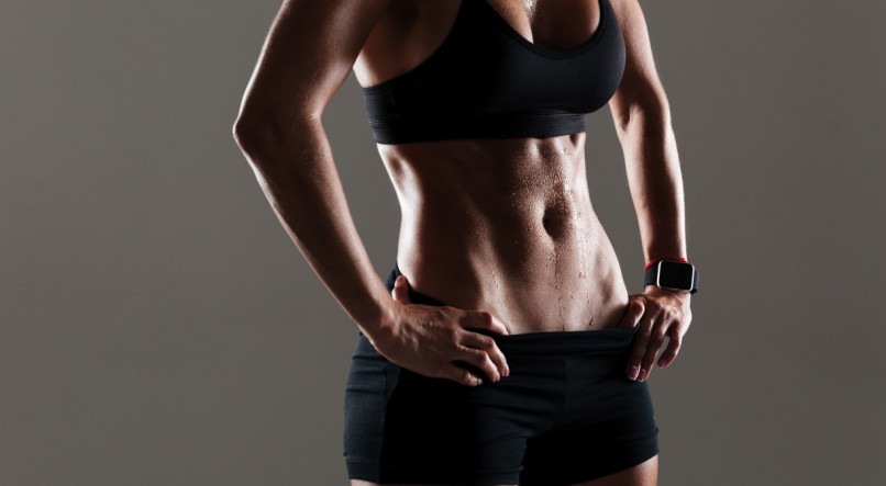 Cropped photo of amazing young sports woman body standing isolated over grey wall.