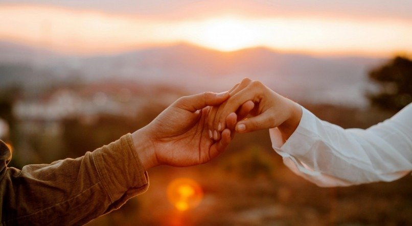 Casal de mãos dadas ao pôr do sol.






