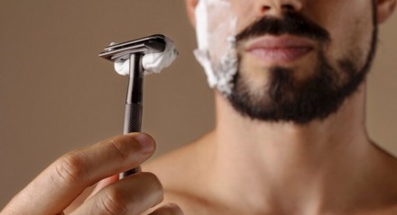 Imagem ilustrativa de homem usando lâmina barbear