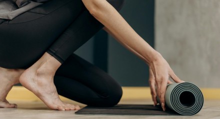 Mulher desenrolando um tapete de exercícios