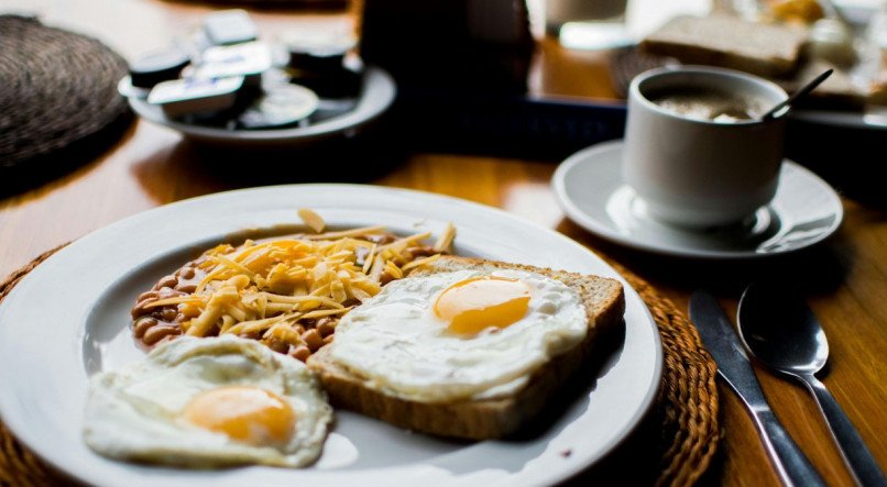 Imagem ilustrativa de uma mesa de café da manhã com pães, ovos e café