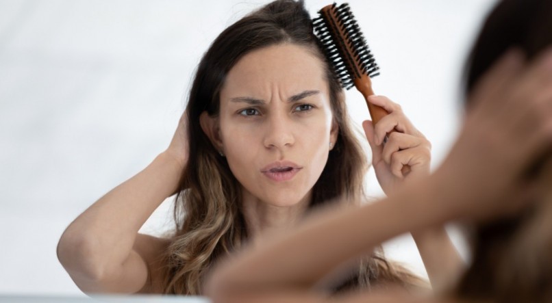 Imagem, mulher passando o pente no cabelo fino. 