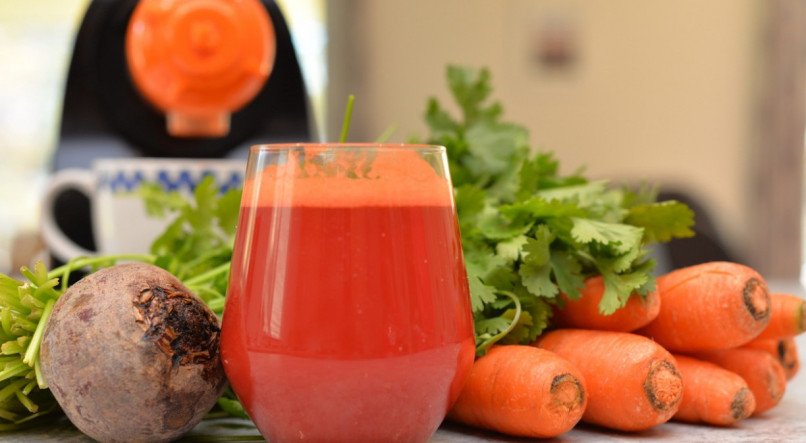Imagem de um copo de suco de cenoura com laranja e beterraba.