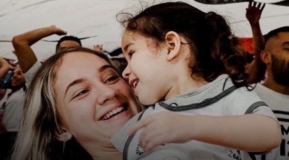 Imagem: mãe corinthiana abraça a filha e as duas sorriem 