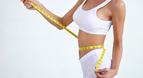 Imagem ilustrativa de mulher medindo a cintura com fita m&eacute;trica para avaliar o peso