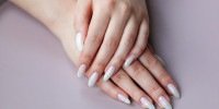 Model woman showing light white nude shellac manicure on the long nails