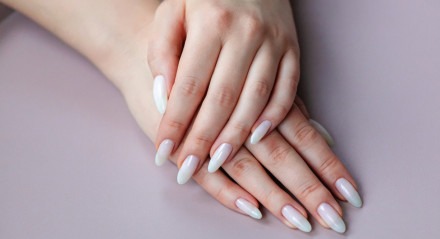 Model woman showing light white nude shellac manicure on the long nails