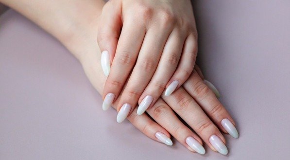 Model woman showing light white nude shellac manicure on the long nails