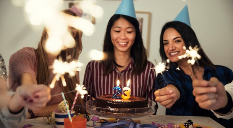 Imagem ilustrativa para frases de feliz anivesário mostrando três amigas celebrando com bolo, velas e decorações festivas